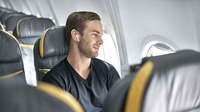 Guy On Plane With Noise Cancelling Earbuds
