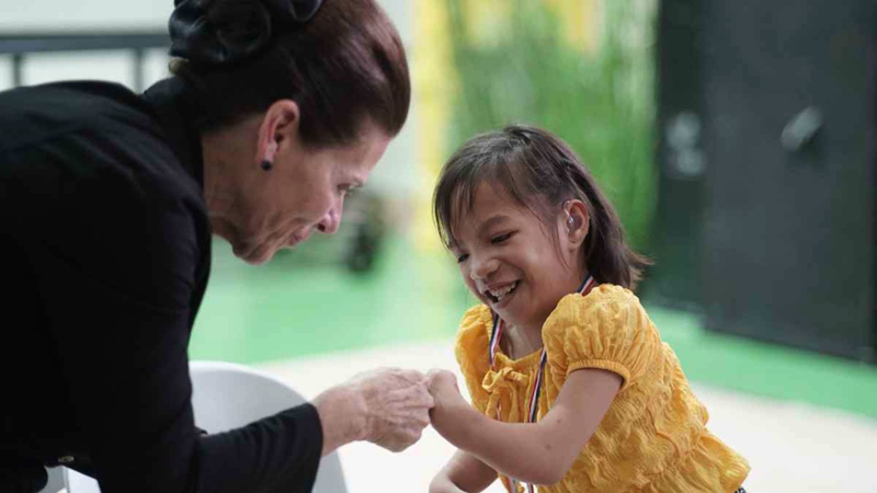 Starkey Hearing Foundation Co-Founder Tani Austin celebrates a young girl's new hearing aids.