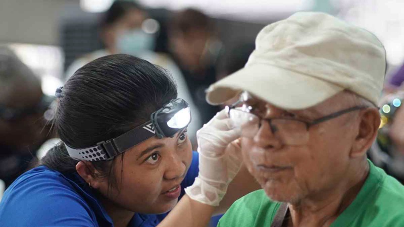 A man gets his ear cleaned by a graduate of the Starkey Hearing Institute program.