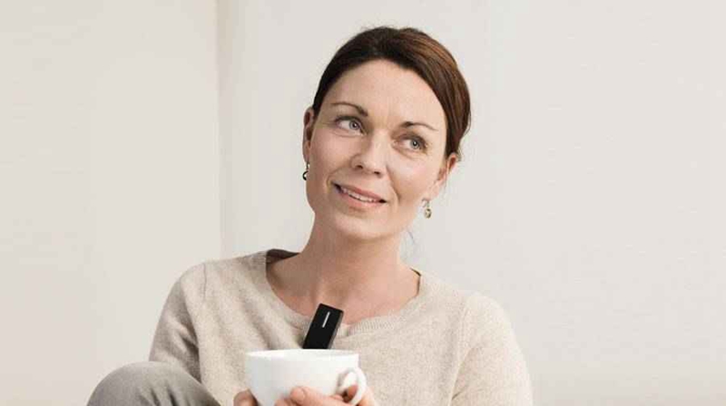A woman uses an Oticon ConnectClip remote microphone