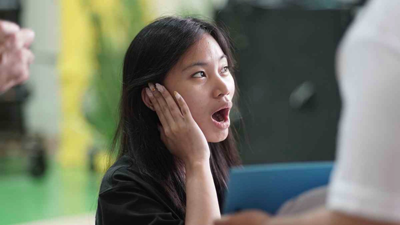 A young woman reacts to amplified sound from a hearing aid.
