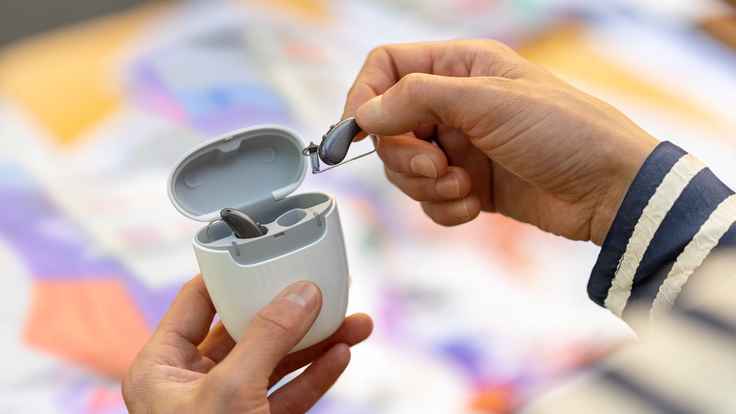 Woman placing her hearing aids in charging case